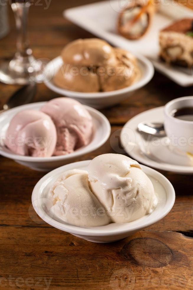 Variety of italian gelato served in bowls on a wooden table photo