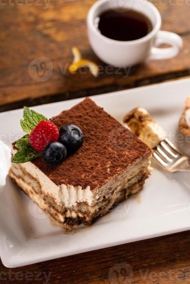 postre de tiramisú servido en un plato blanco con espresso foto