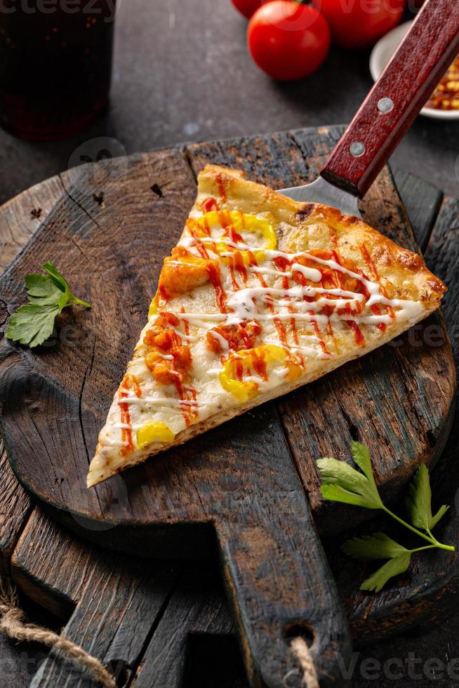 Chicken BBQ pizza with hot sauce, slice on a board photo