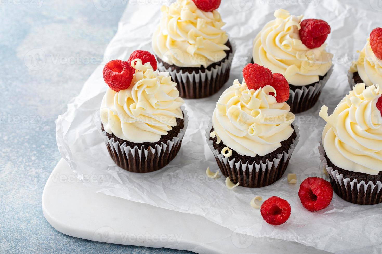Chocolate cupcakes with white chocolate frosting and raspberries photo