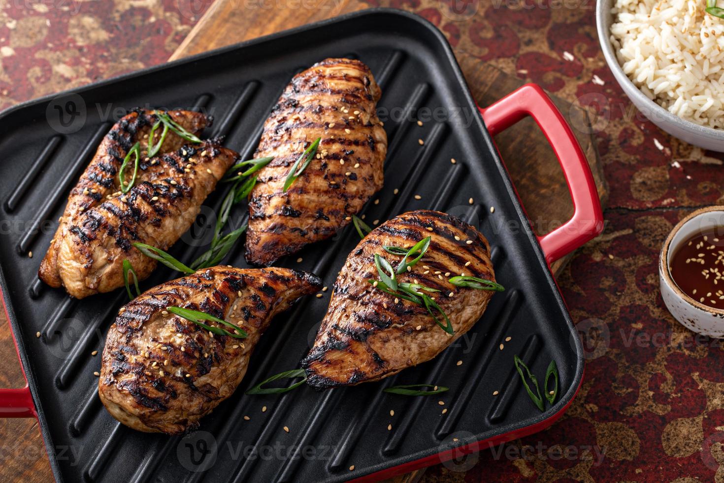 Grilled teriyaki chicken breast on a grill pan with green onions