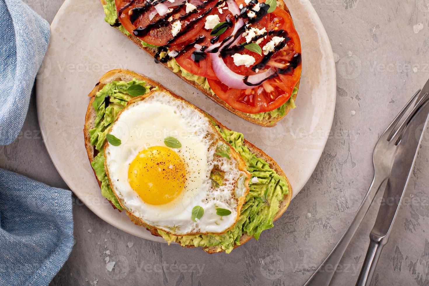 Avocado toasts with fried egg and heirloom tomatoes photo