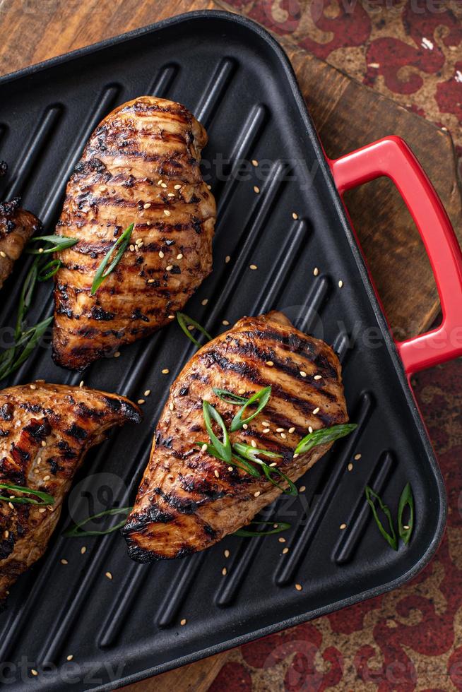 Grilled teriyaki chicken breast on a grill pan with green onions photo