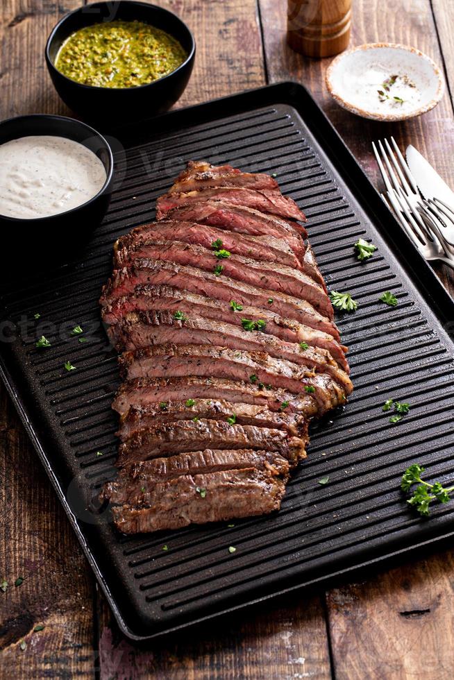 bistec de flanco a la parrilla con salsa chimichurri en una sartén a la parrilla foto