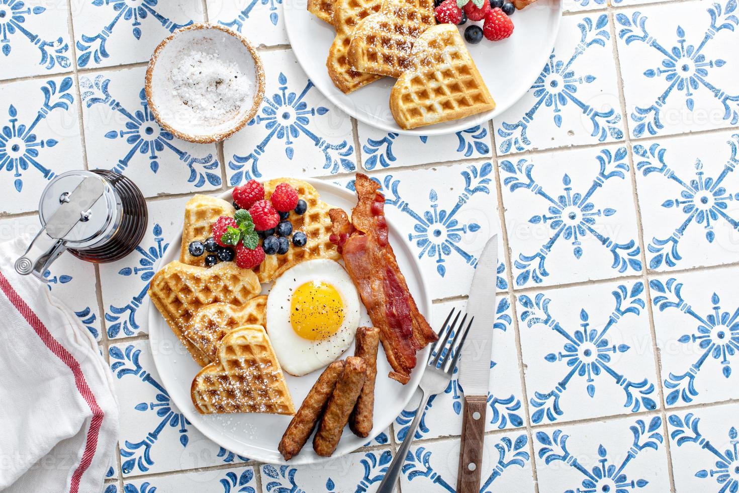 Breakfast table with waffles. fried egg, bacon and sausage photo