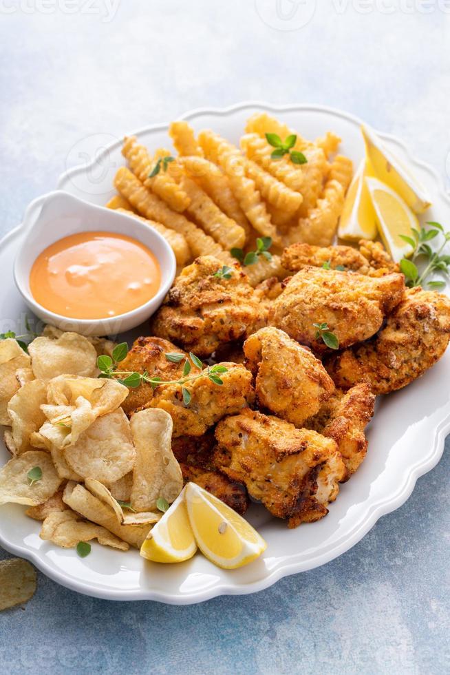 Fish and chips on a serving platter with dipping sauce photo
