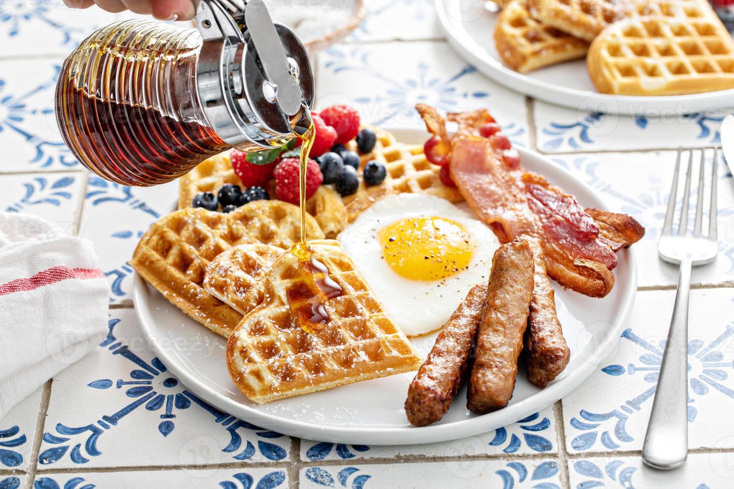 mesa de desayuno con gofres. huevo frito, bacon y salchicha foto