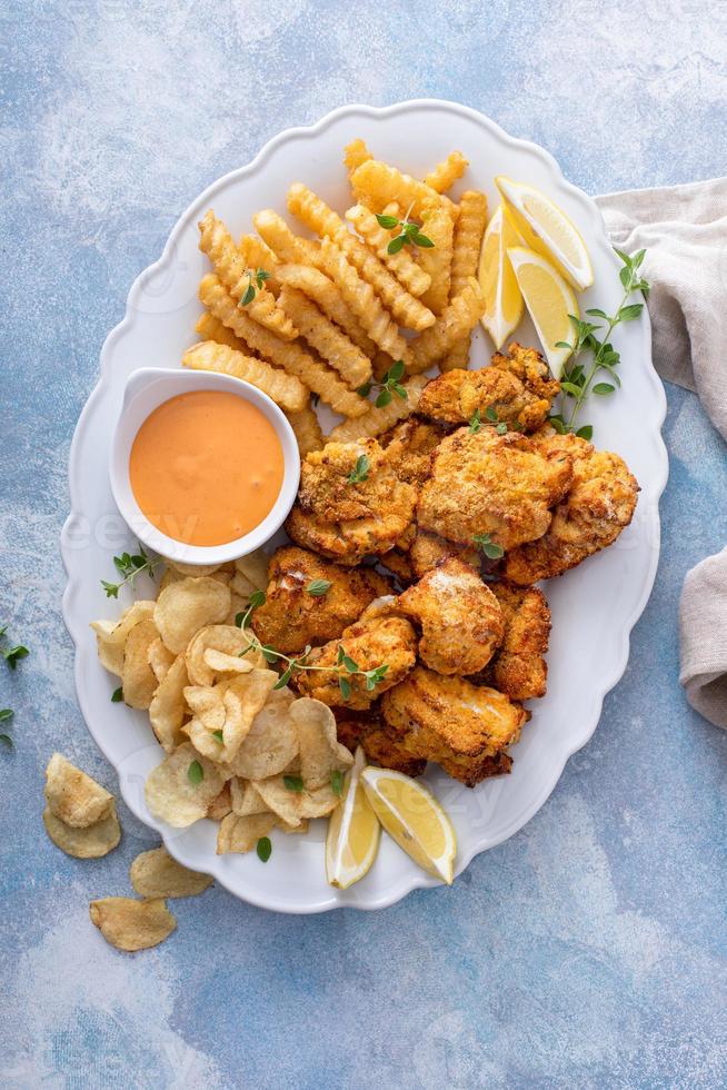 Fish and chips on a serving platter with dipping sauce photo