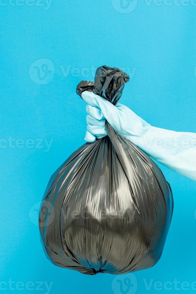 concepto más limpio, mano en guantes de goma y bolsa de plástico con residuos de basura foto
