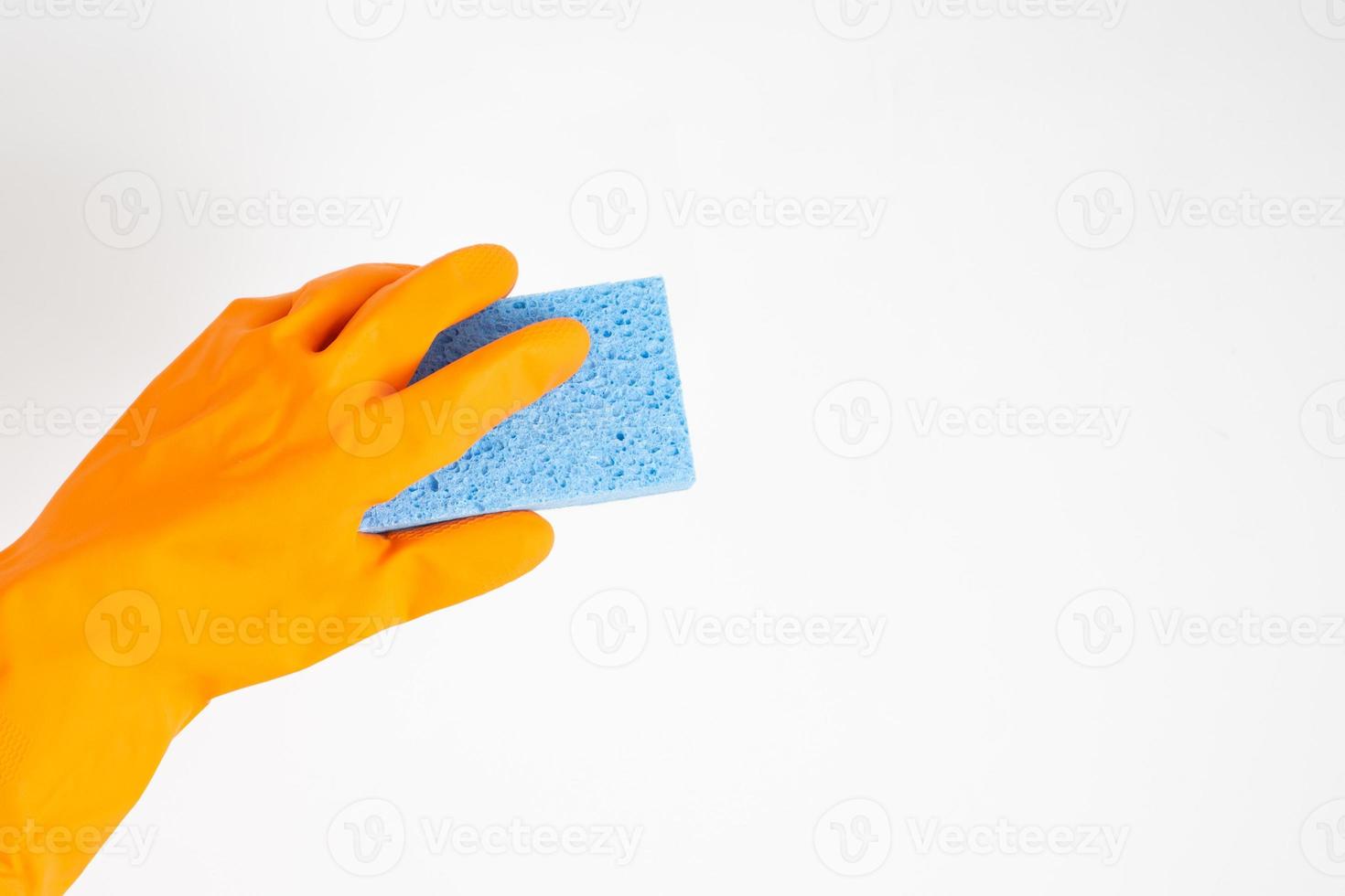 concepto más limpio, mano en guantes de goma naranja y esponja azul claro para limpiar en casa foto