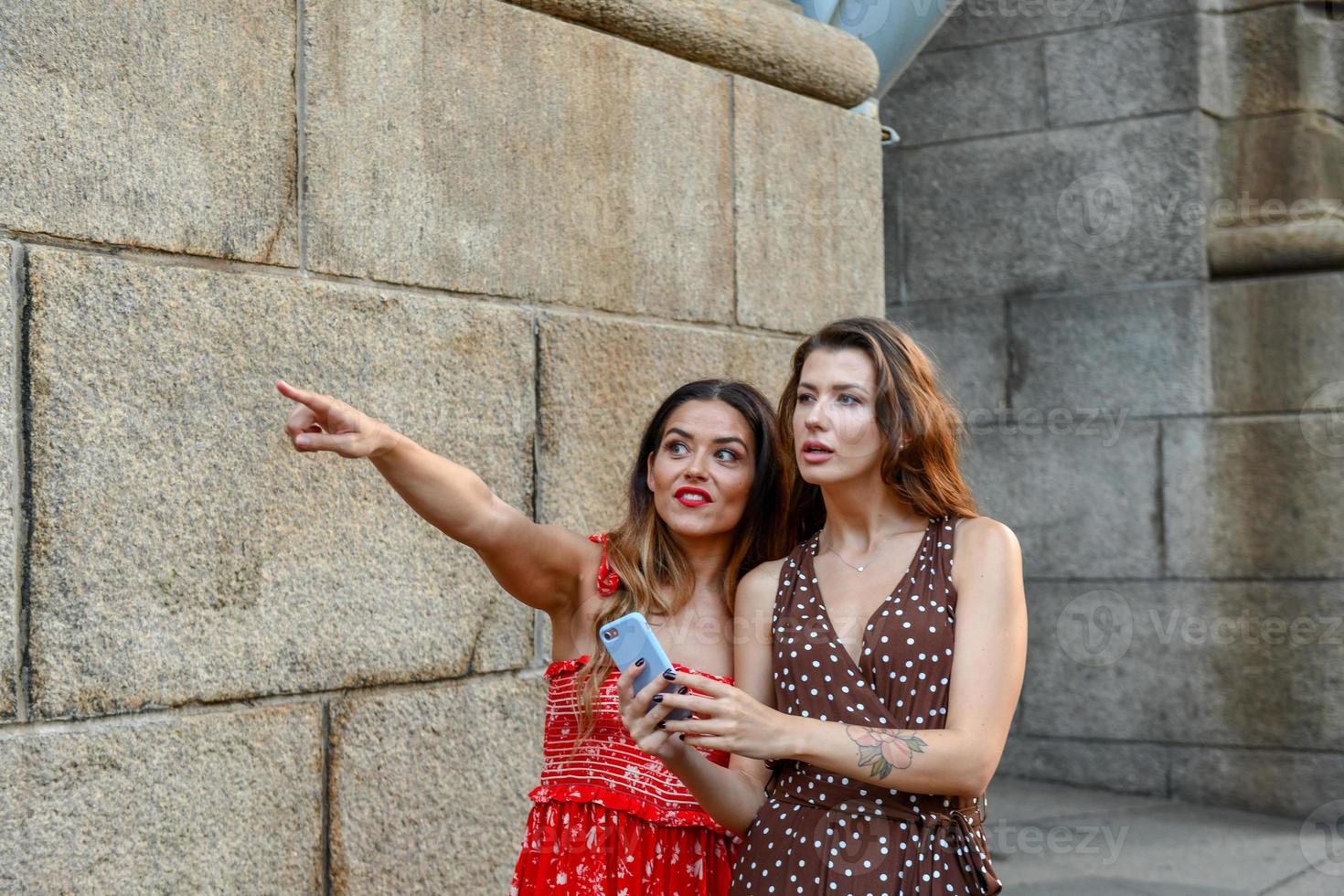 dos chicas perdidas interactuando con un teléfono móvil para obtener direcciones en la ciudad de nueva york foto