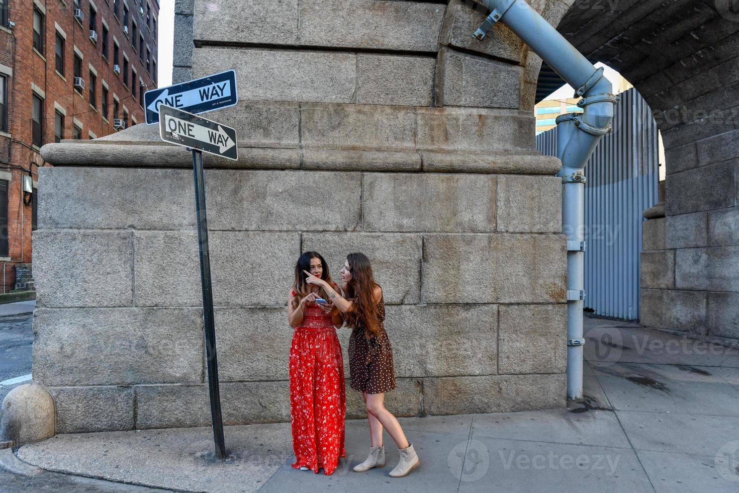 dos chicas perdidas interactuando con un teléfono móvil para obtener direcciones en la ciudad de nueva york foto