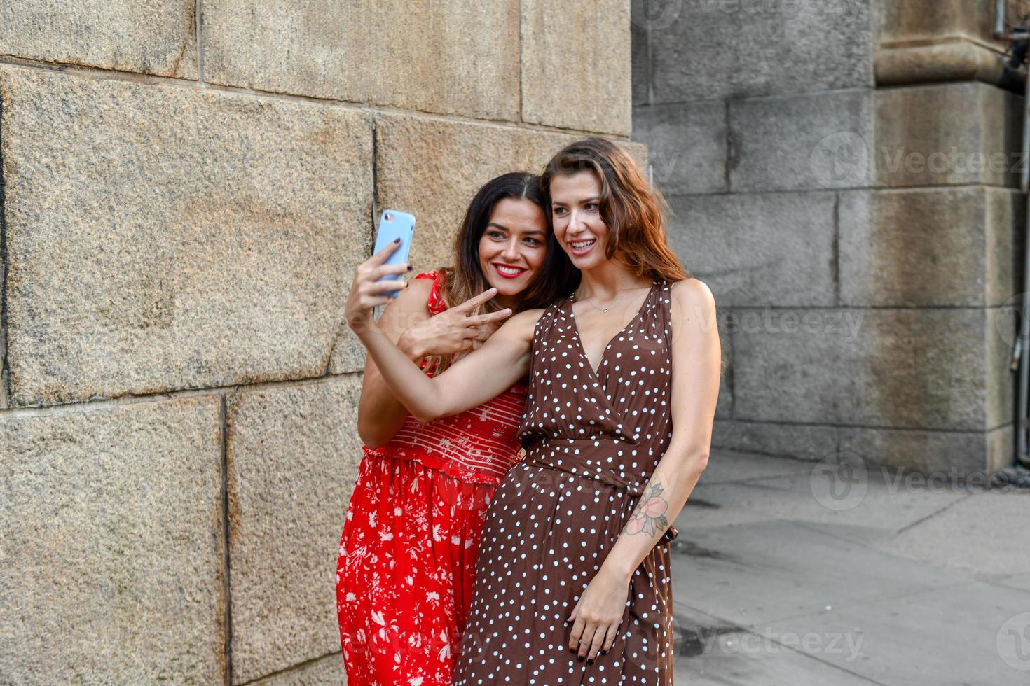 dos chicas interactuando con un teléfono móvil y tomándose selfies tontas en la ciudad de nueva york foto