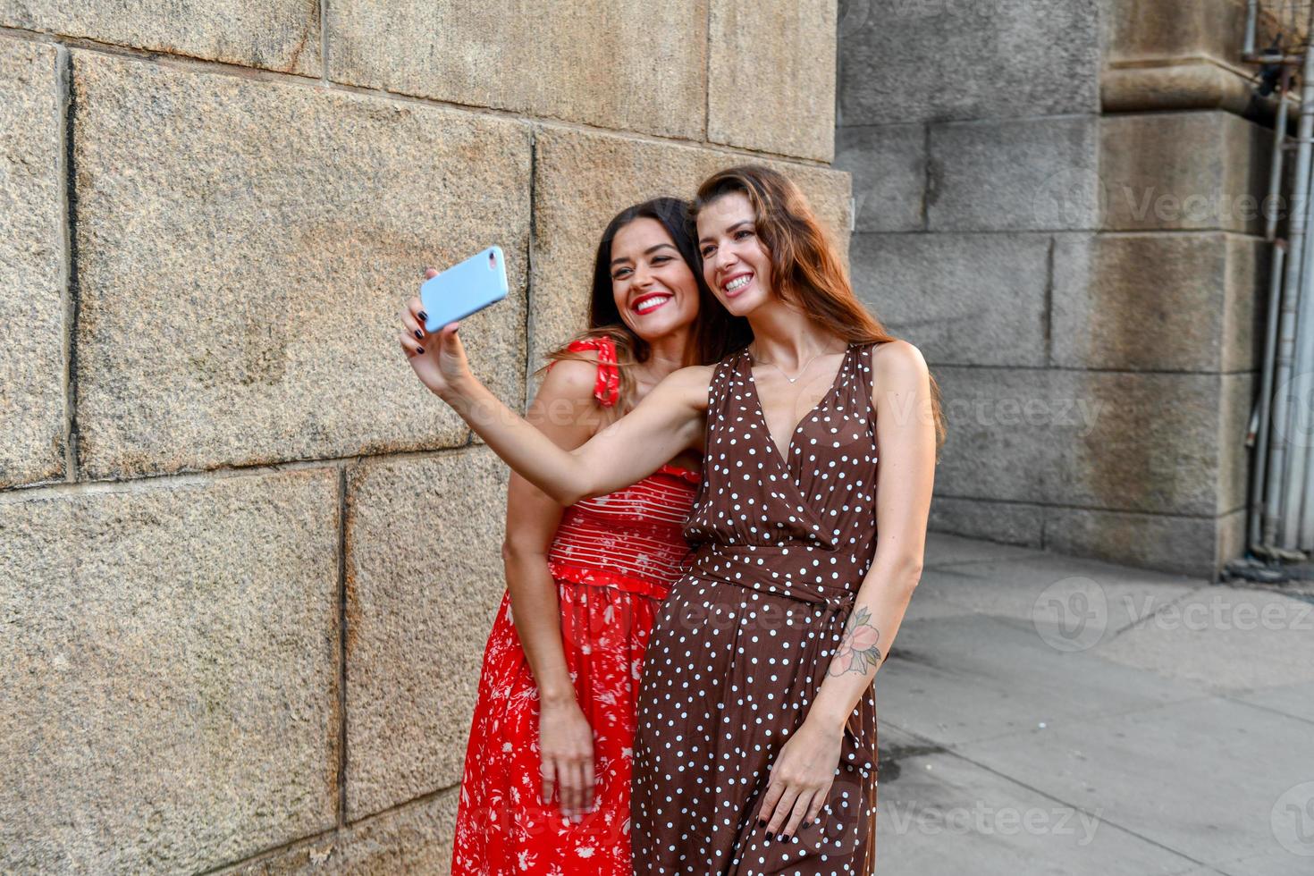 Two girls interacting with a mobile phone and taking silly selfie photos in New York City