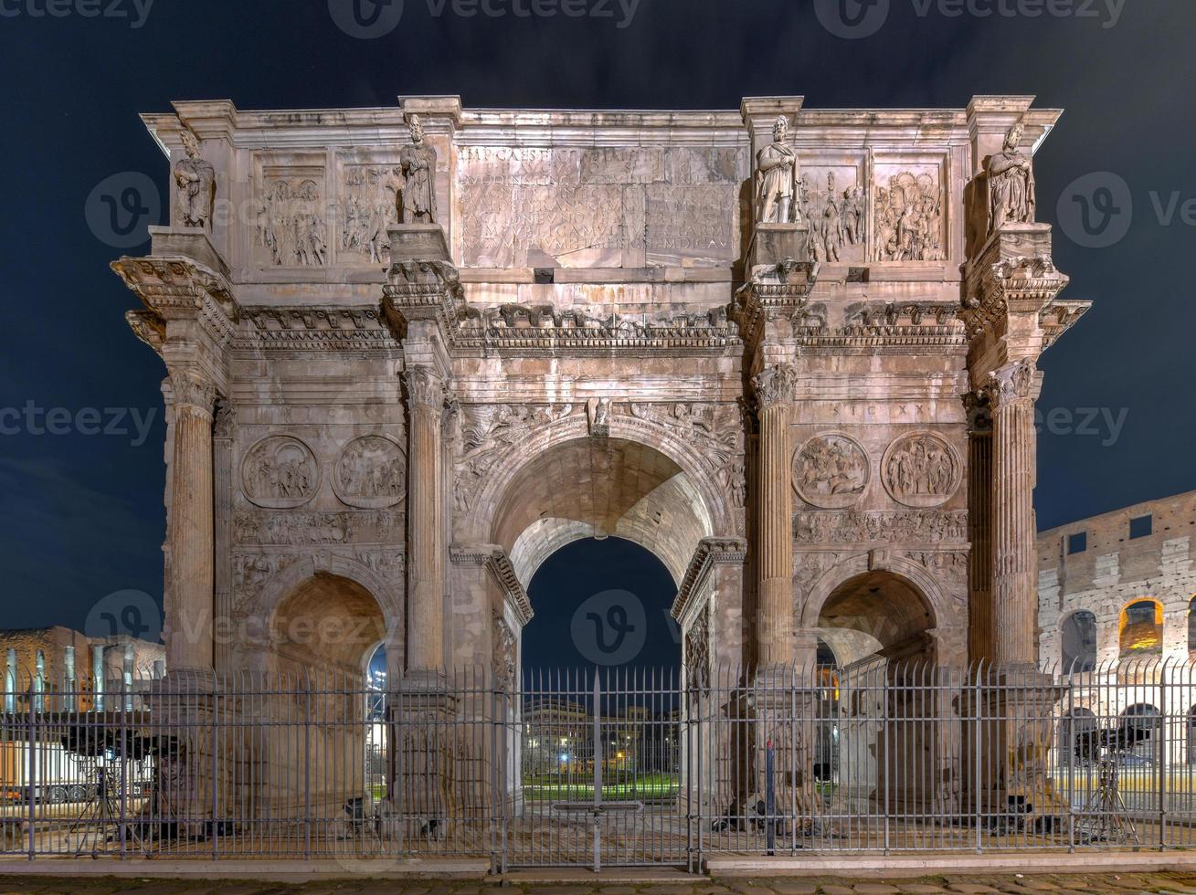 The Arch of Constantine is a triumphal arch in Rome, situated between the Colosseum and the Palatine Hill in Rome, Italy at night. photo