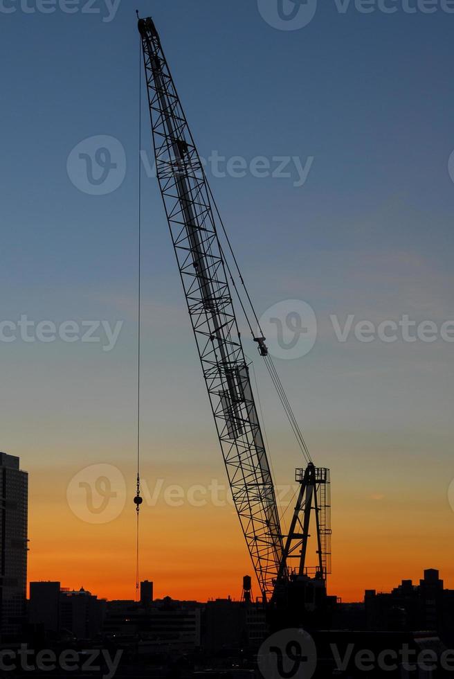 Construction against a background of a silhouette of New York City at sunset. photo