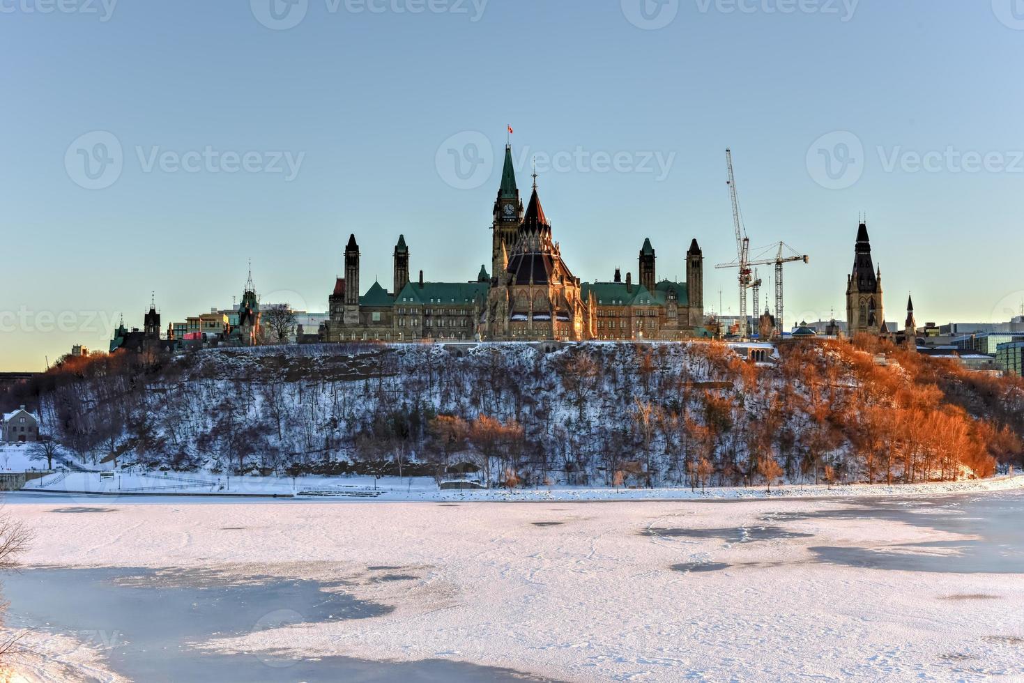la colina del parlamento y la casa del parlamento canadiense en ottawa, canadá, al otro lado del río congelado de ottawa durante el invierno. foto