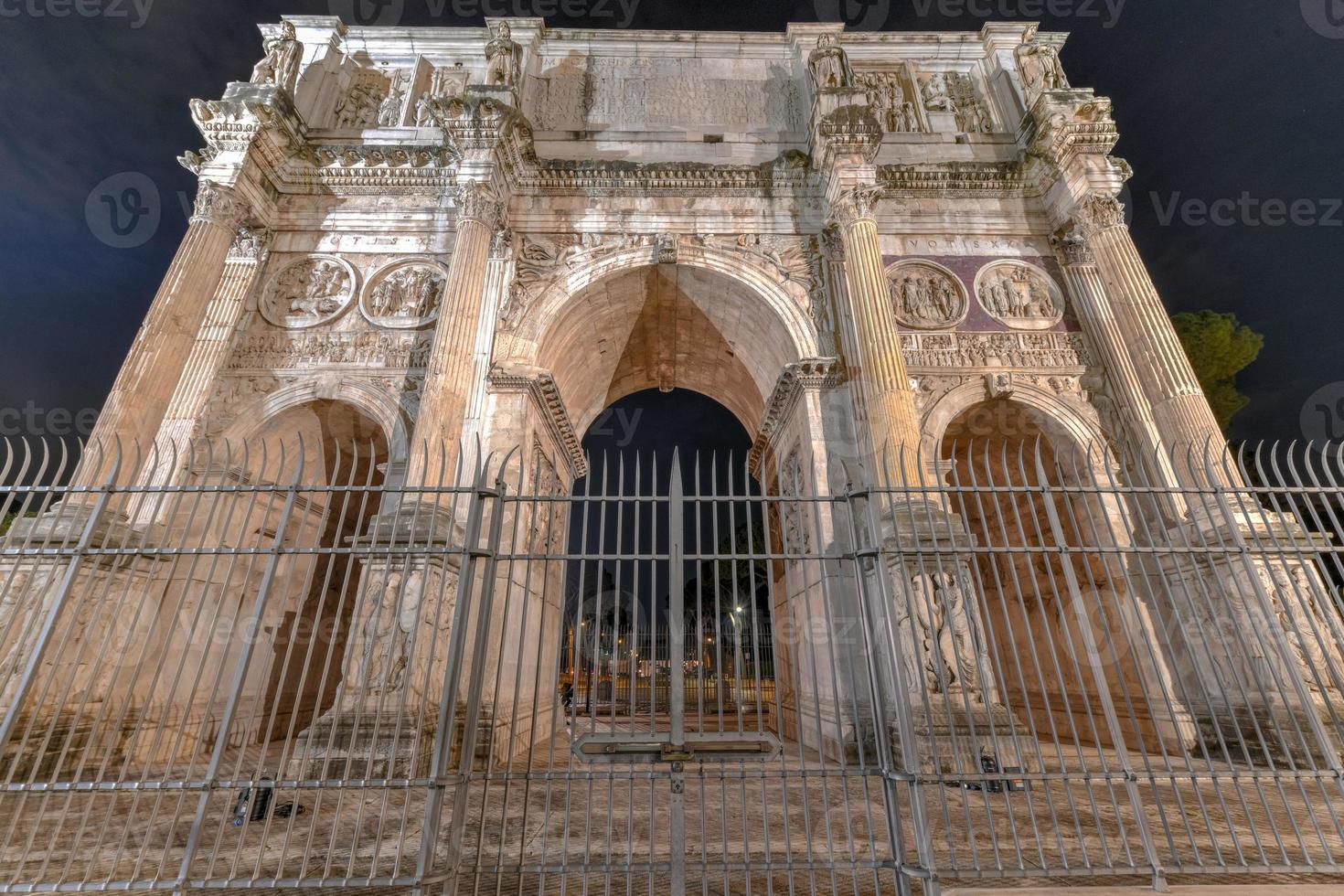 The Arch of Constantine is a triumphal arch in Rome, situated between the Colosseum and the Palatine Hill in Rome, Italy at night. photo