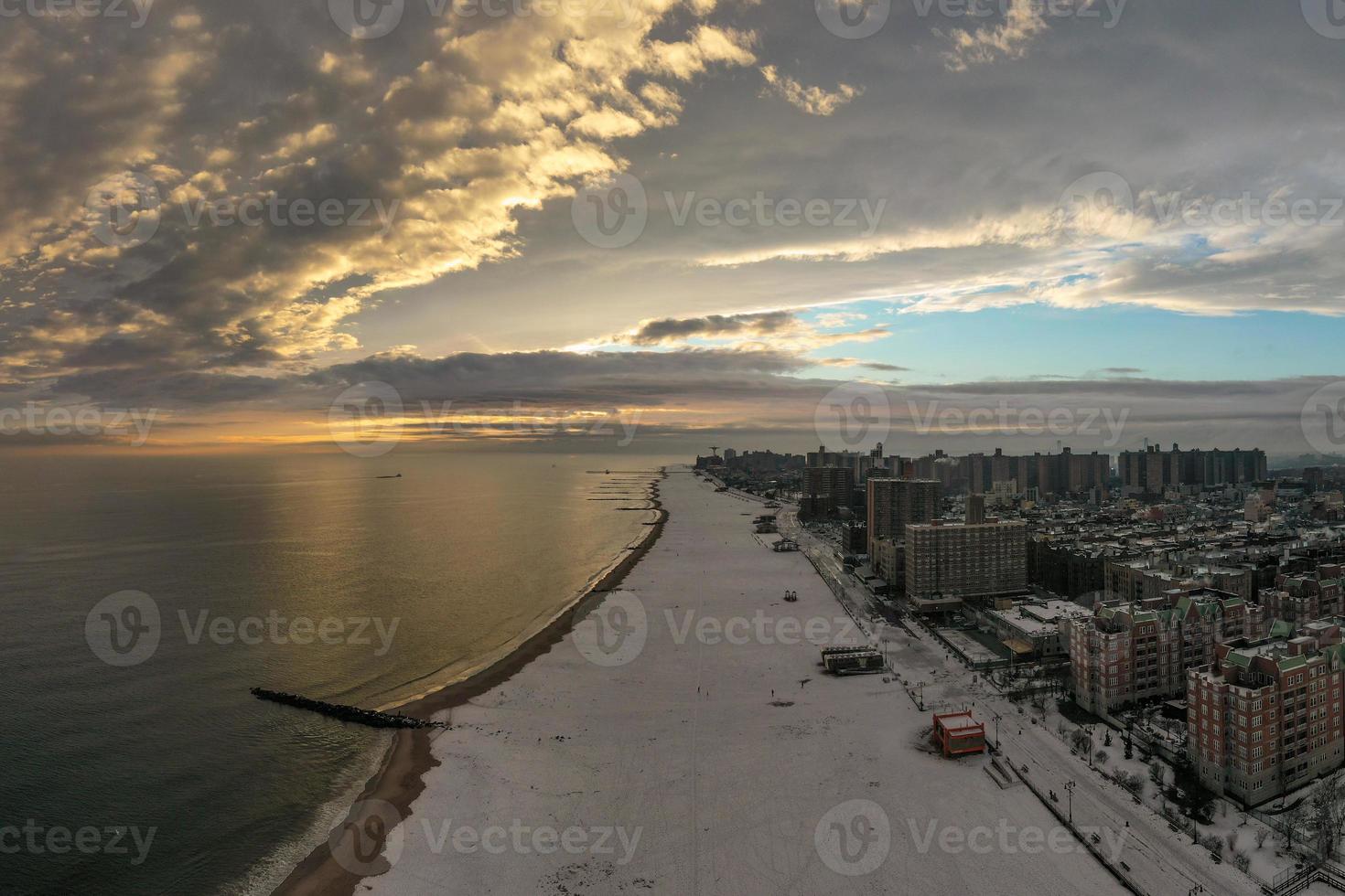 vista aérea de una playa de coney island cubierta de nieve durante el invierno al atardecer en brooklyn, nueva york foto