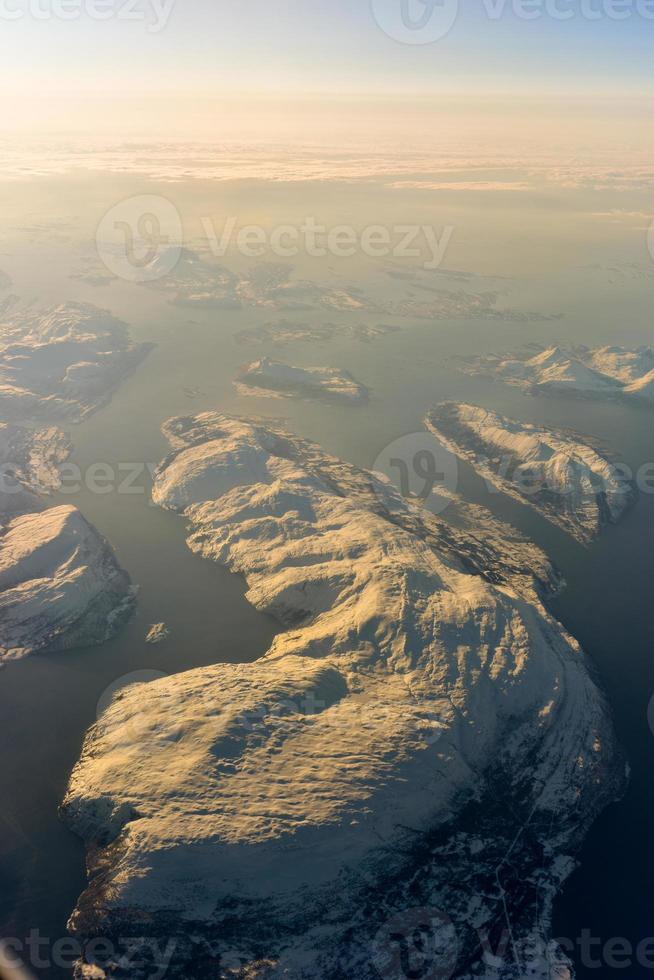 una vista aérea de las montañas cubiertas de nieve de los fiordos de noruega en el invierno. foto