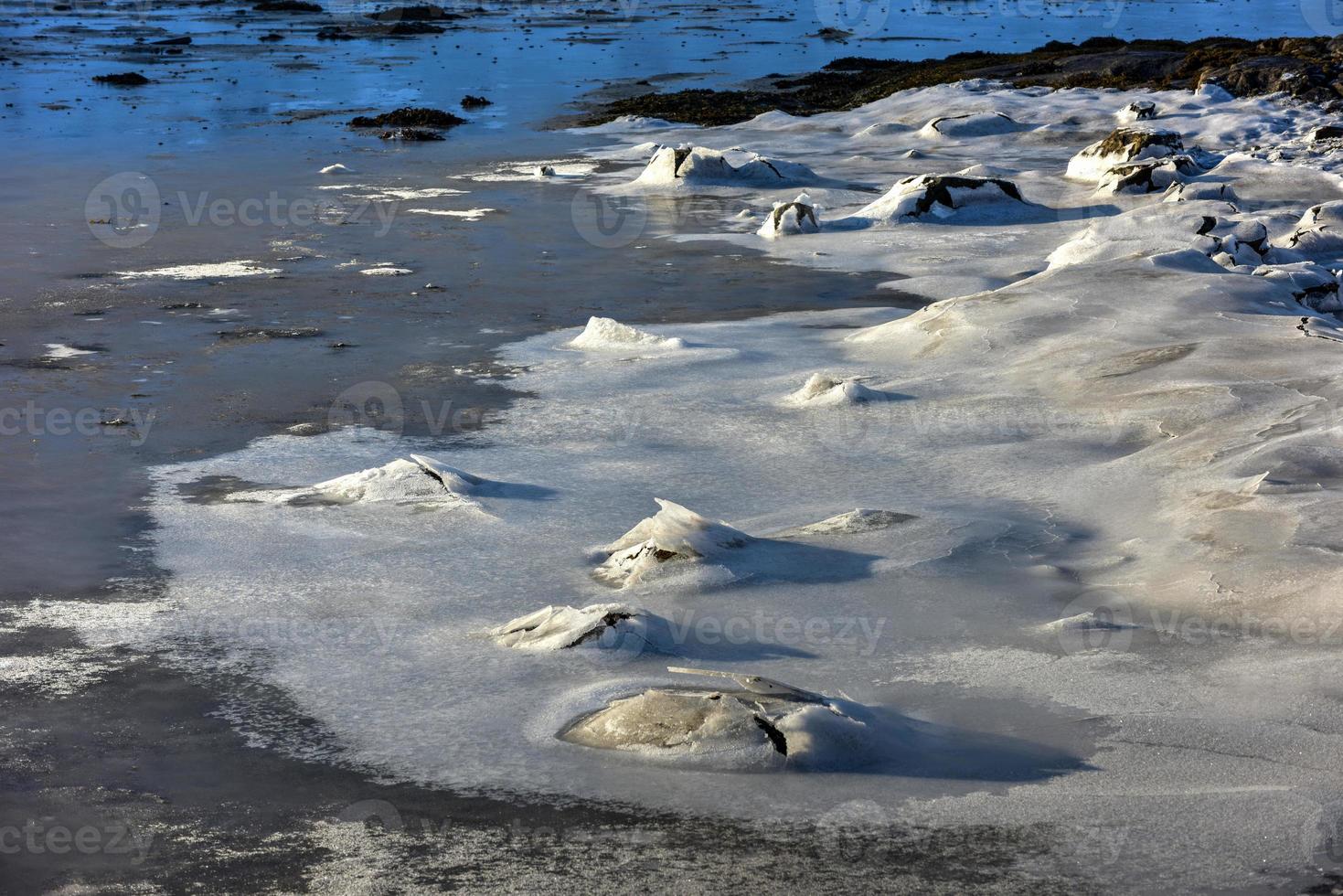 Rock cracking through the ice in Boosen in the Lofoten Islands, Norway in the winter. photo