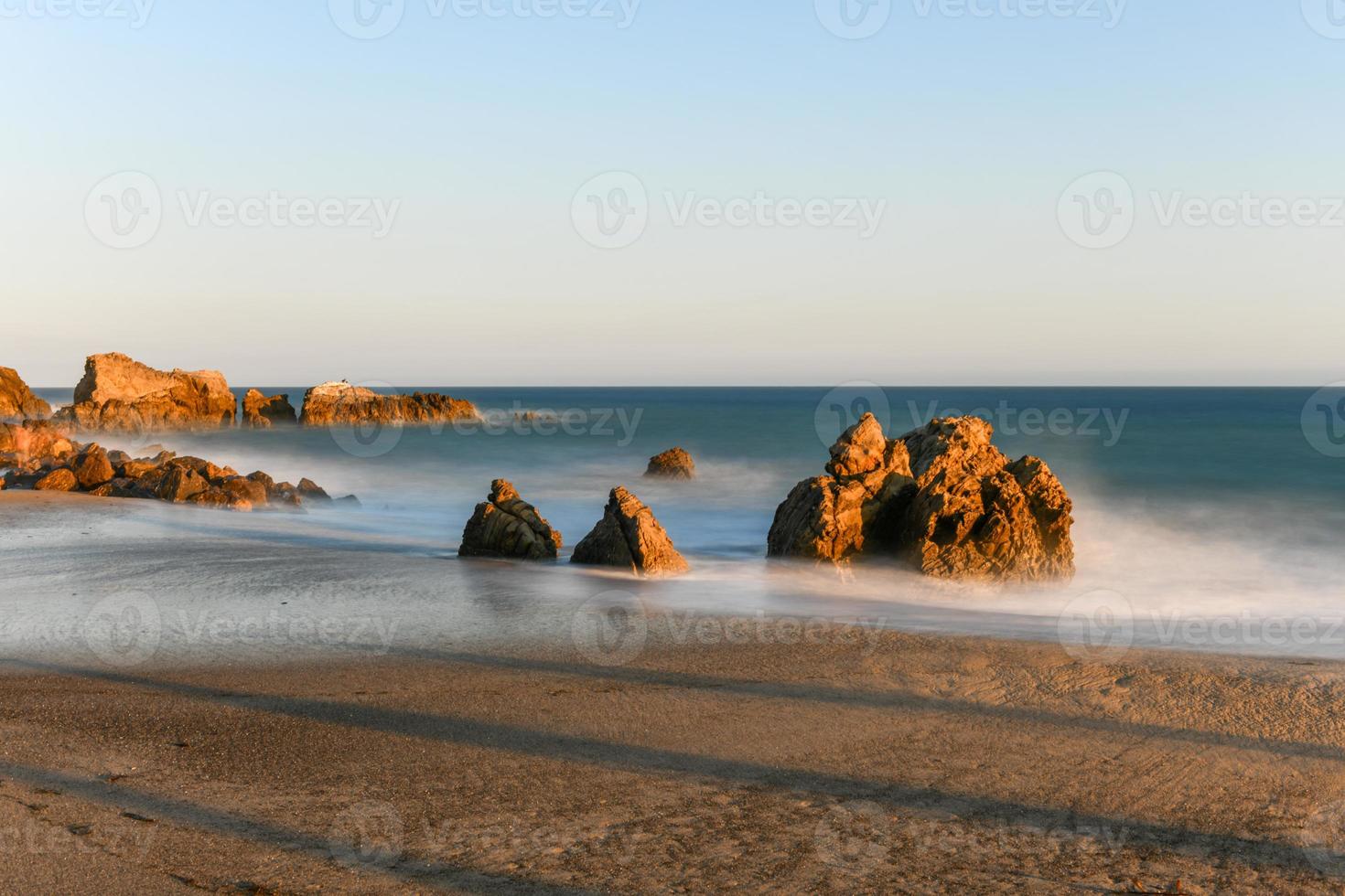 Stunning long-exposure view of smooth waves crashing into rock formations at sunset, Sequit Point, Leo Carrillo State Beach, Malibu, California photo