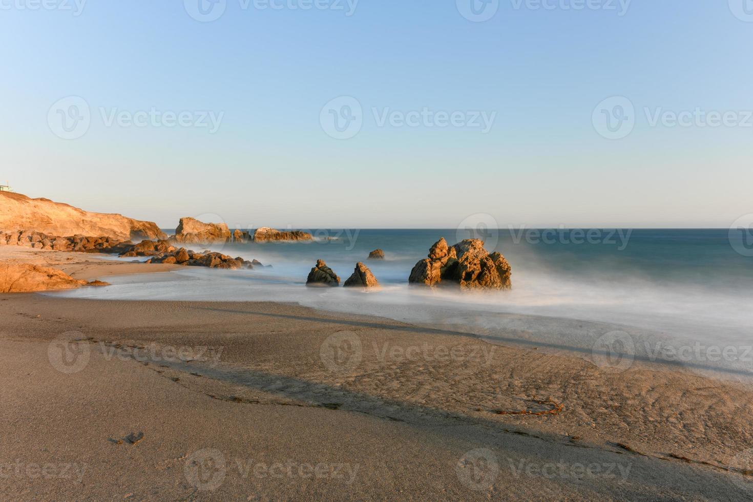 Stunning long-exposure view of smooth waves crashing into rock formations at sunset, Sequit Point, Leo Carrillo State Beach, Malibu, California photo