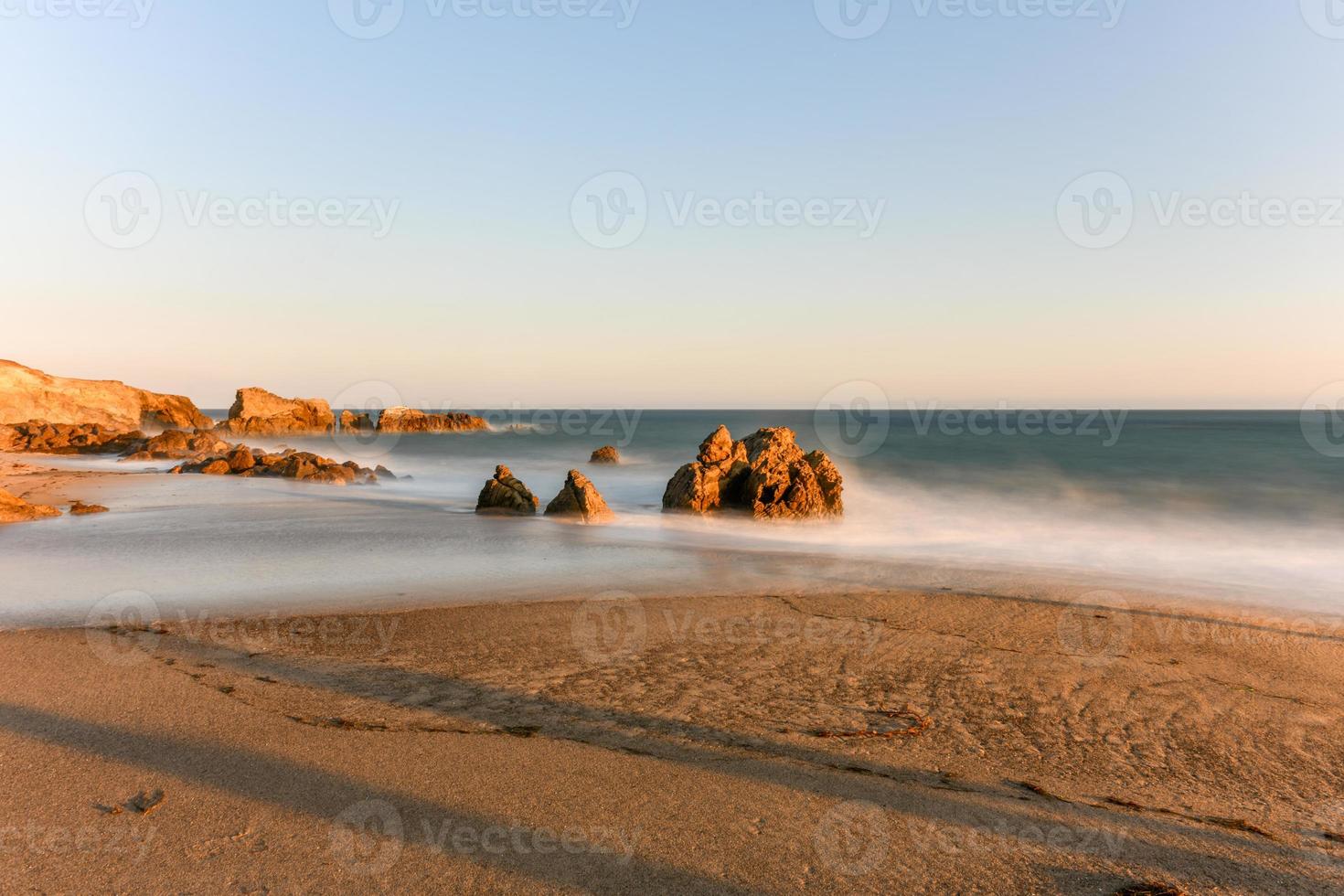 Stunning long-exposure view of smooth waves crashing into rock formations at sunset, Sequit Point, Leo Carrillo State Beach, Malibu, California photo