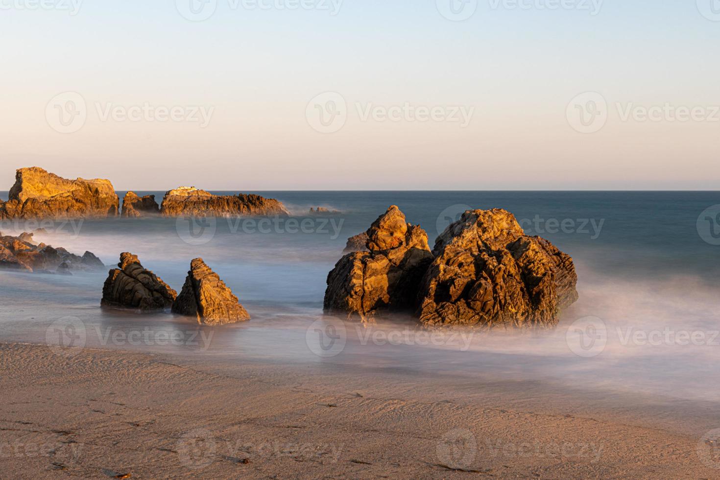 Stunning long-exposure view of smooth waves crashing into rock formations at sunset, Sequit Point, Leo Carrillo State Beach, Malibu, California photo