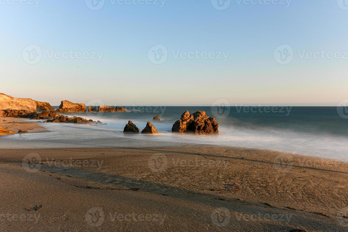 Stunning long-exposure view of smooth waves crashing into rock formations at sunset, Sequit Point, Leo Carrillo State Beach, Malibu, California photo