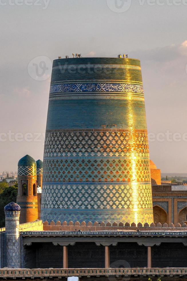 Kalta Minor Minaret and the historic architecture of Itchan Kala, walled inner town of the city of Khiva, Uzbekistan a UNESCO World Heritage Site. photo