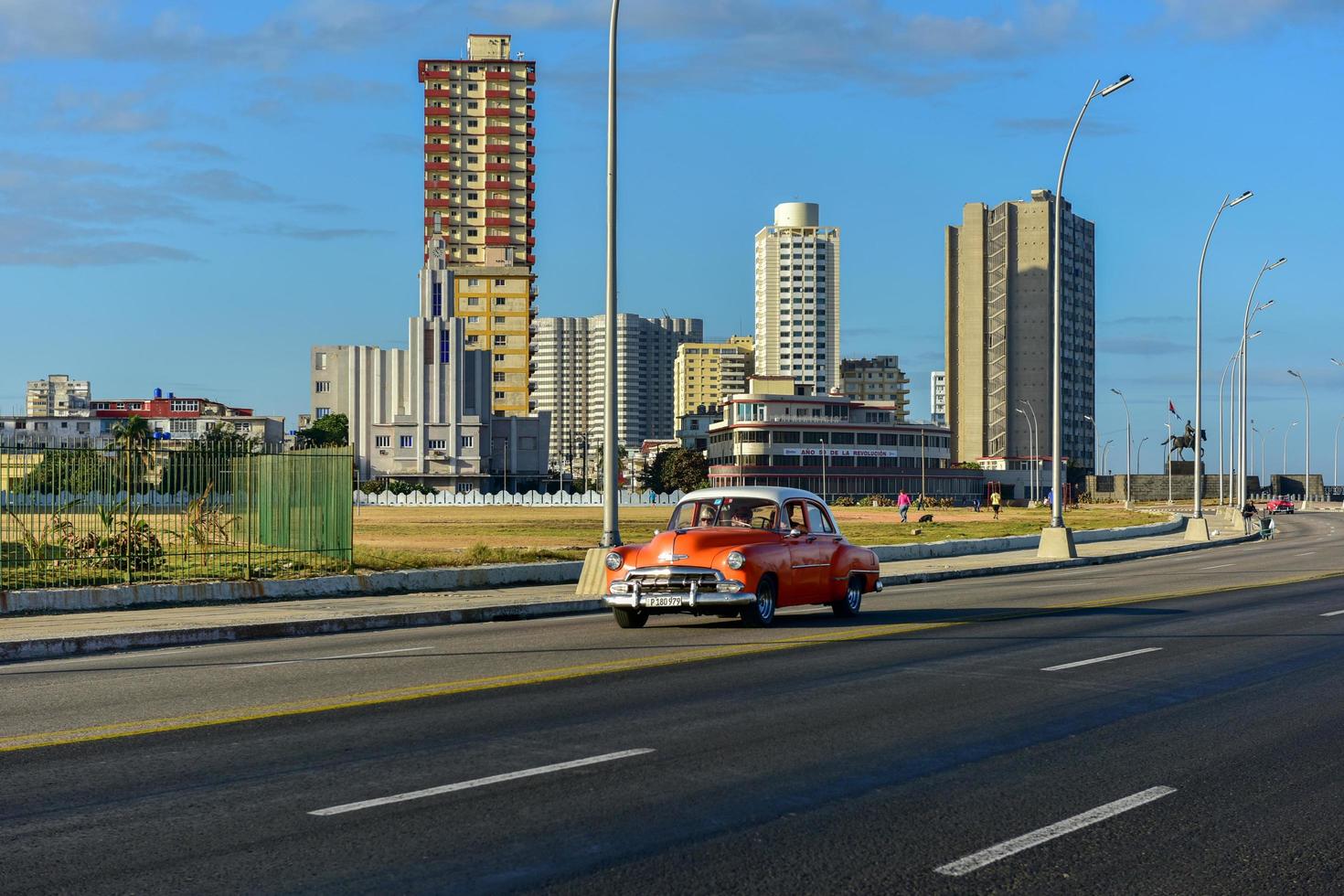 Havana, Cuba - Jan 15, 2017 -  Classic car driving along the Malecon with the Casa de las Americas in the background in Havana, Cuba. photo