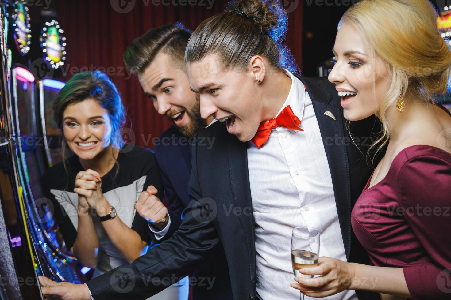 grupo de amigos jugando máquinas tragamonedas en el casino foto