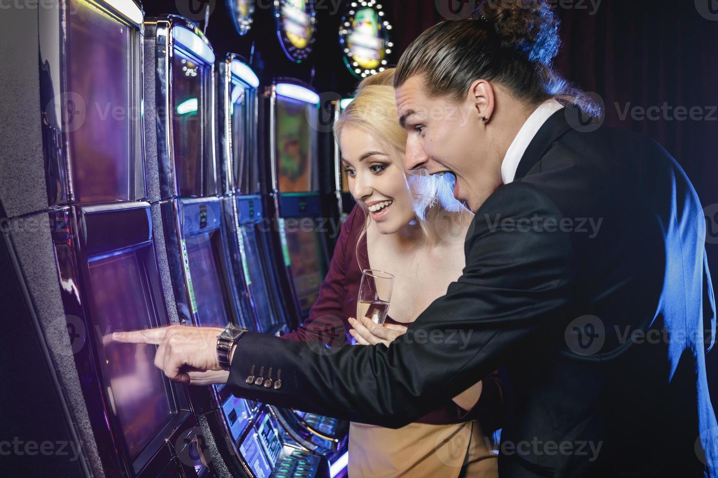 Young couple playing slot machines in the casino photo