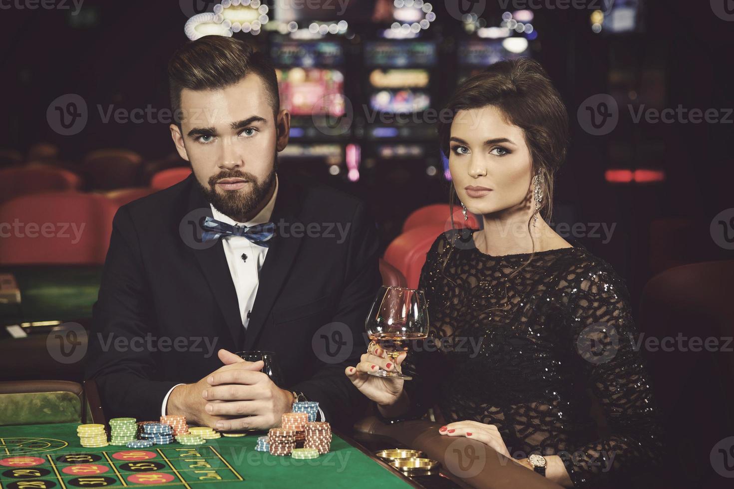 Beautiful and rich couple playing roulette in the casino photo
