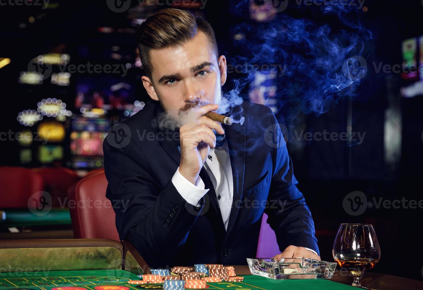 Rich handsome man smoking cigar in the casino photo