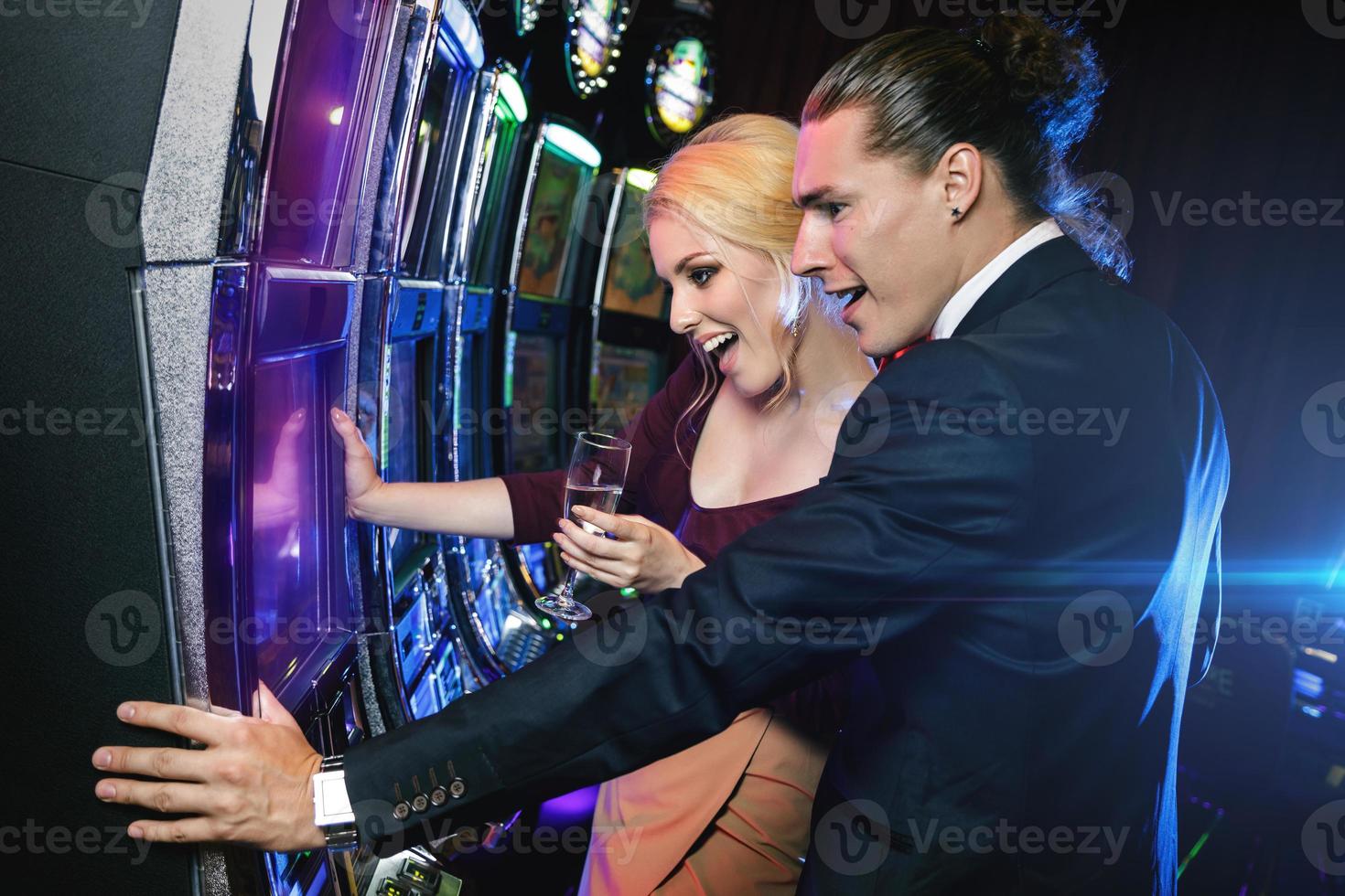 Young couple playing slot machines in the casino photo