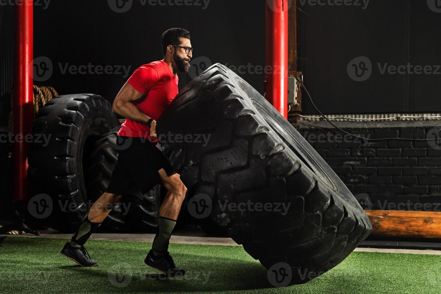 Strong sportsman doing a tire flip exercise photo