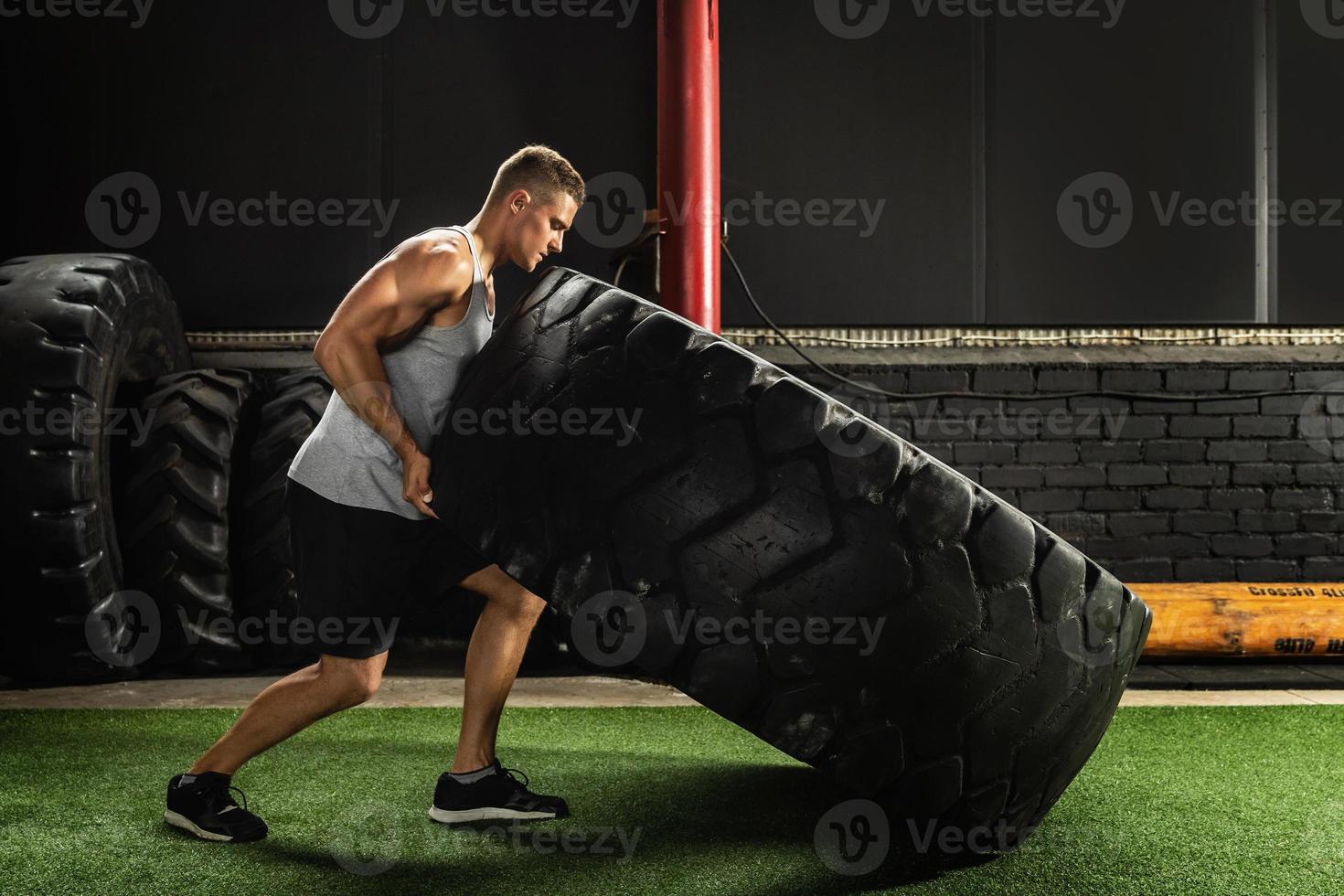 Strong sportsman doing a tire flip exercise photo
