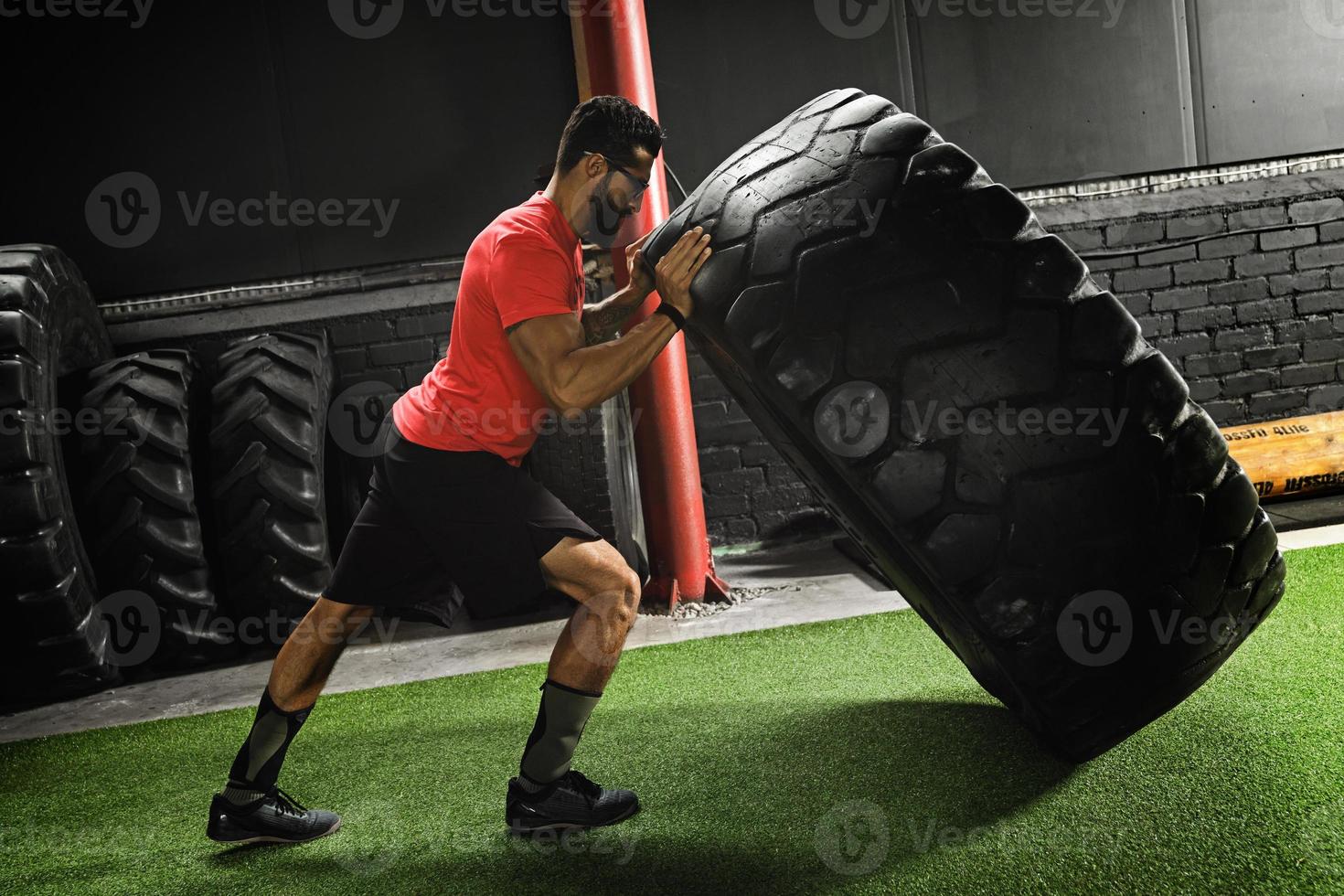 Strong sportsman doing a tire flip exercise photo