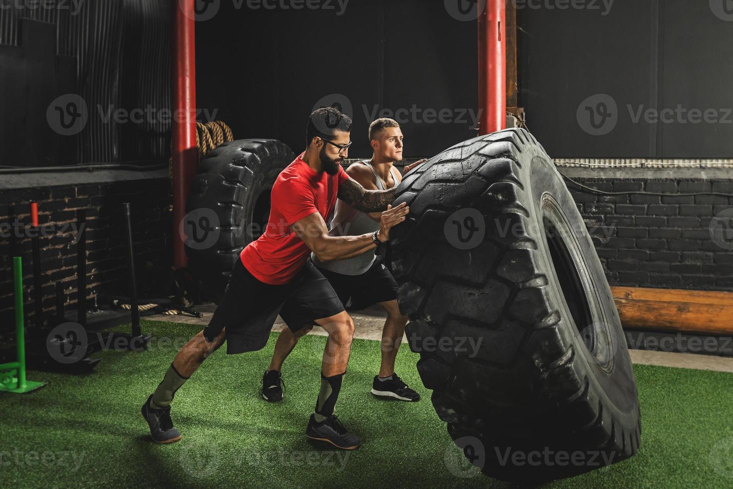 Two strong men doing a tire flip exercise photo