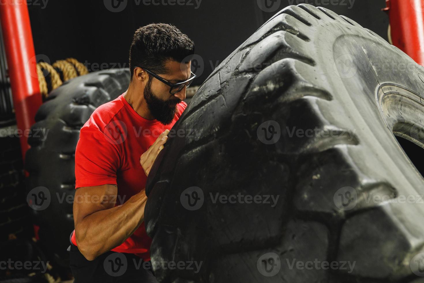 Strong sportsman doing a tire flip exercise photo