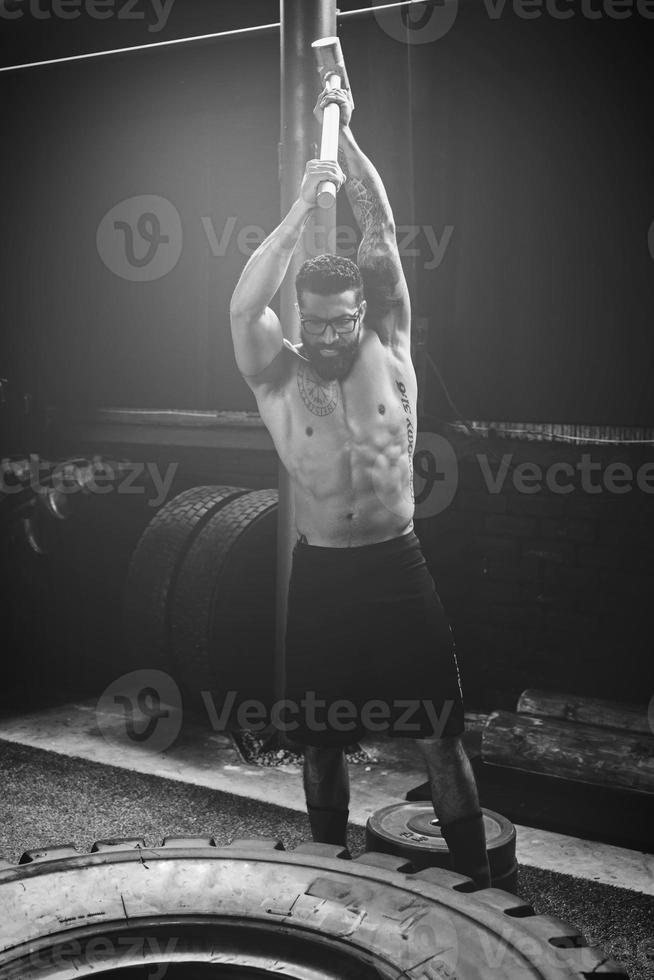 Man is hitting tire with a sledgehammer during his cross training