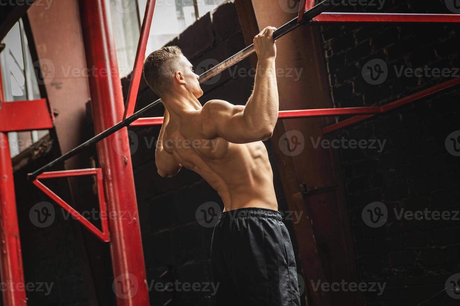 Strong man doing pull up exercise in the gym photo
