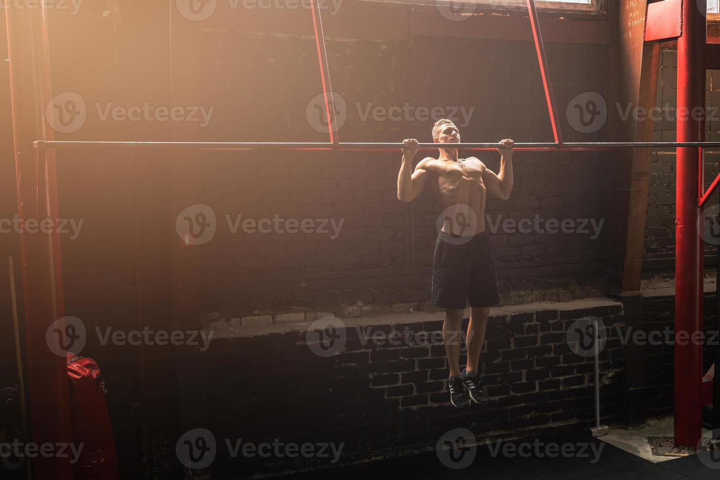 Strong man doing pull up exercise in the gym photo