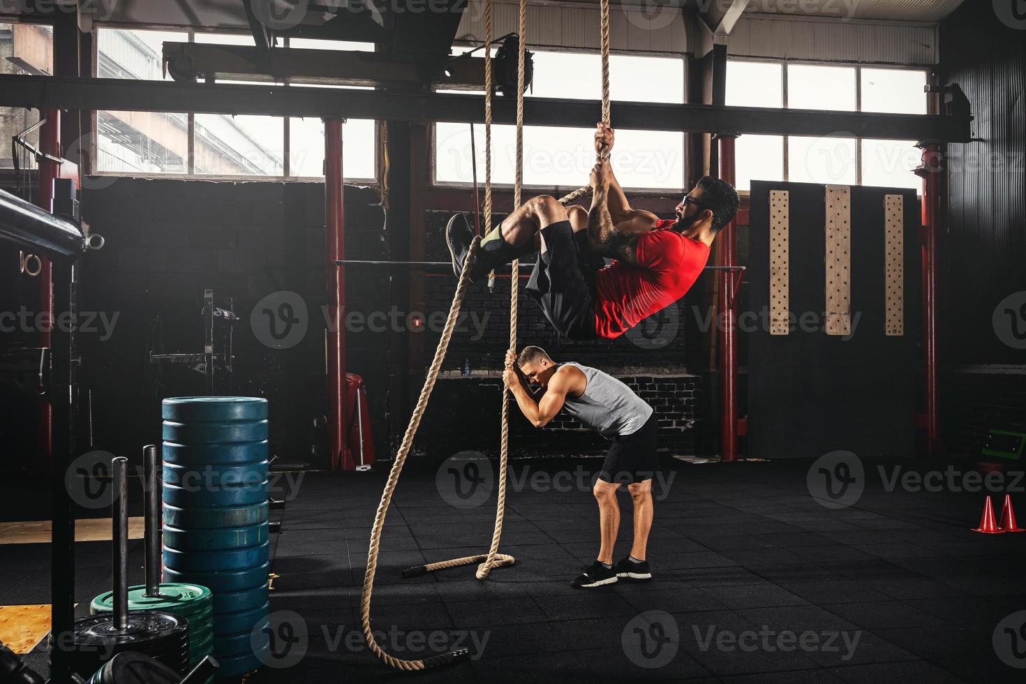 Two men doing rope climbing exercise in the cross training gym