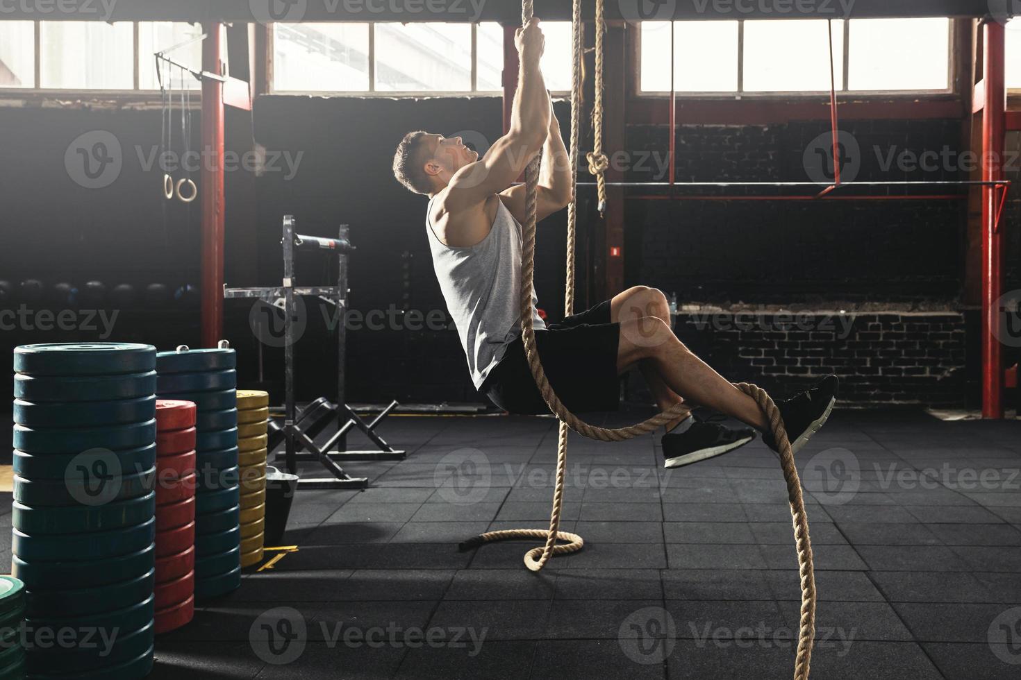 Sportsman doing rope climbing exercise in the cross training gym