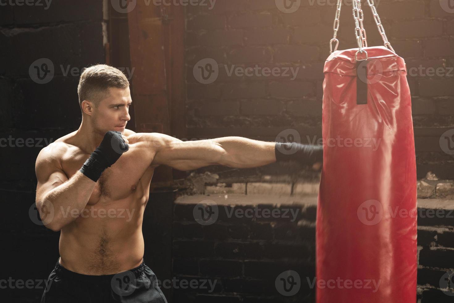 luchador de mma joven y fuerte y saco de boxeo rojo foto