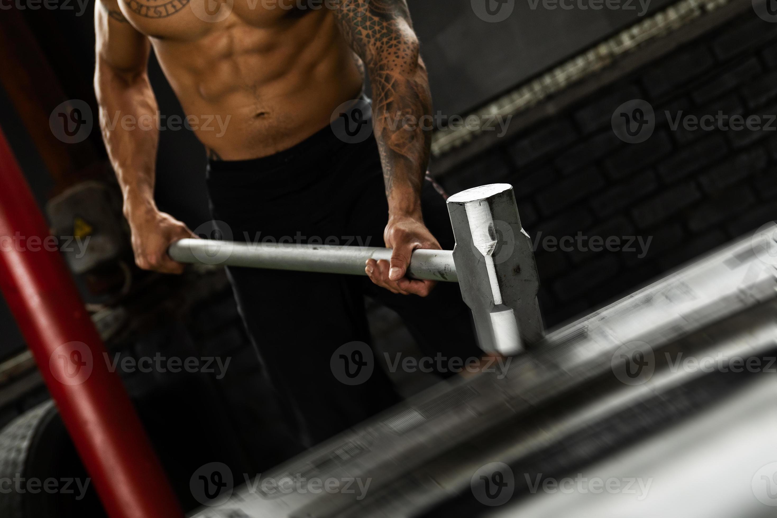 Man is hitting tire with a sledgehammer during his cross training