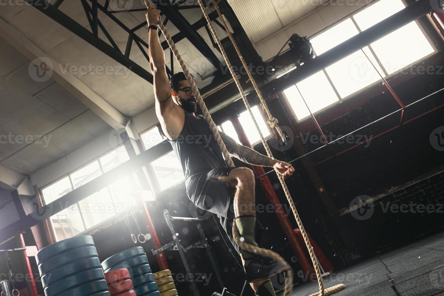 Sportsman doing rope climbing exercise in the cross training gym photo